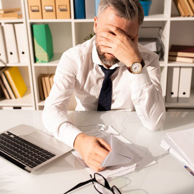 Frustrated tired man working with papers in office